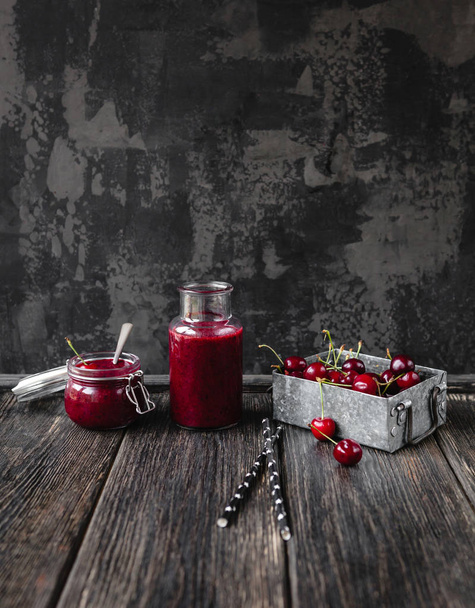 Свежий здоровый смузи на деревенском столе с вишнями и соломинками
 - Фото, изображение