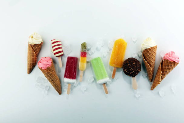 Vanilla frozen yogurt or soft ice cream in waffle cone and Colorful popsicle  - Fotó, kép