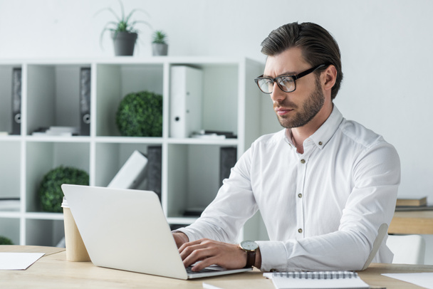 confiant jeune homme d'affaires travaillant avec ordinateur portable au bureau moderne
 - Photo, image