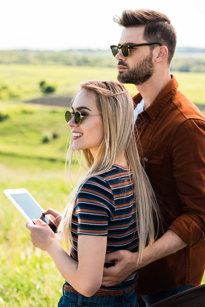 young stylish couple in sunglasses standing with digital tablet - Valokuva, kuva