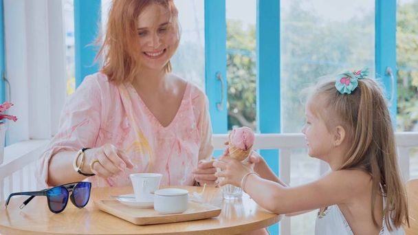 Young mother and her little daughter spending time in a cafe with ice cream - Foto, afbeelding