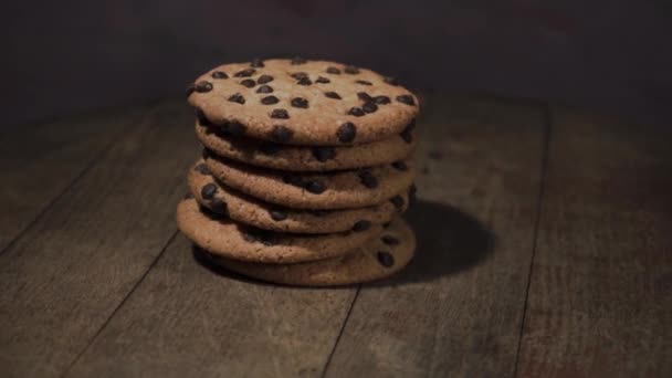 Soubory cookie s čokoládové drobky na dřevěný stůl, rotace 360 stupňů. Krásné tmavé pozadí. - Záběry, video
