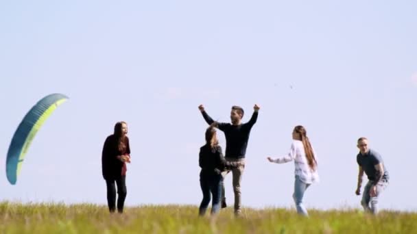 Młodzi przyjaciele szczęśliwy zabawy w lato pole przez latający żagiel - Materiał filmowy, wideo