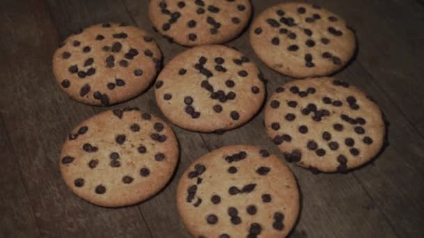 Biscoitos com migalhas de chocolate em uma mesa de madeira, rotação 360 graus. Belo fundo escuro
. - Filmagem, Vídeo