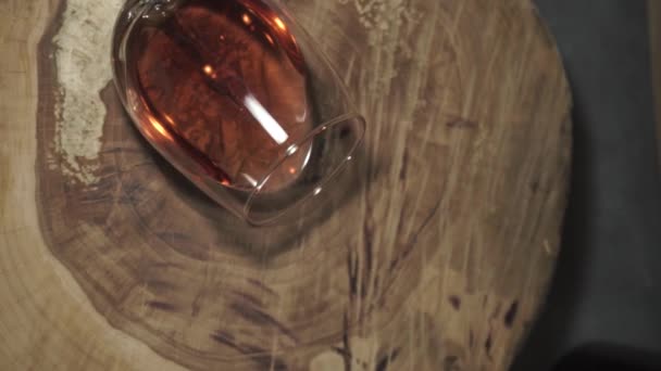 Glass of white wine on a round, cracked wooden table, rotation 360 degrees. Beautiful wooden barrel and bottle background. - Filmagem, Vídeo