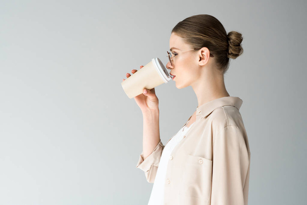 a gyönyörű fiatal nő kávét iszik, a tovább elszigetelt a szürke oldalnézete - Fotó, kép