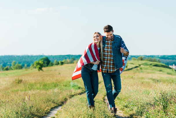 heureux jeune couple avec drapeau américain sur prairie rurale, concept de fête de l'indépendance
 - Photo, image
