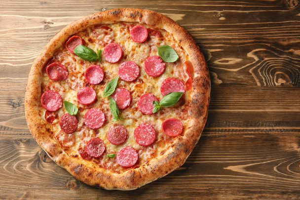 Delicious pizza with salami on wooden background - Photo, Image