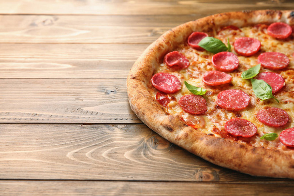 Délicieuse pizza avec salami sur fond bois, gros plan
 - Photo, image