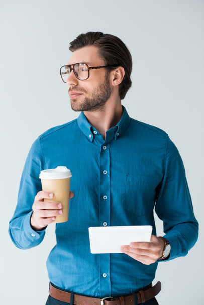 joven seguro de sí mismo con taza de papel de café y tableta aislado en blanco
 - Foto, imagen