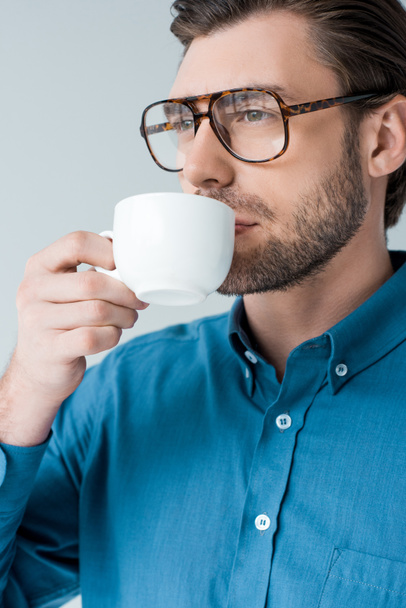 close-up portrait of young man drinking coffee from cup isolated on white - Фото, изображение