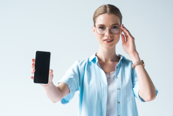 hermosa mujer joven sosteniendo teléfono inteligente con pantalla en blanco aislado en blanco
 - Foto, Imagen