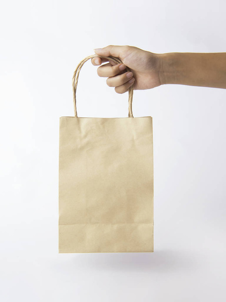 Hand holding Blank brown paper bag for mockup template advertising and branding background.  - Foto, Imagem