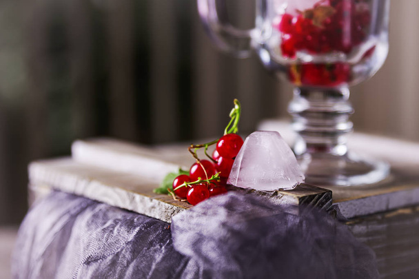 Κόκκινη σταφίδα και τα παγάκια σε ένα διάφανο ποτήρι στο τραπέζι - Φωτογραφία, εικόνα