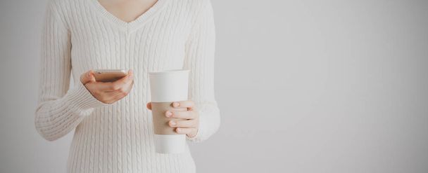 Soft focus young girl hands using smartphone and hold a cup of coffee. Copy space. Communication coffee break concept. Banner - Foto, imagen
