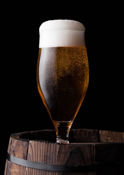 Vidrio frío de cerveza artesanal en barrica de madera vieja sobre fondo negro
 - Foto, Imagen