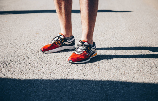 Κοντινό πλάνο του άνδρα που φοράει παπούτσια για τρέξιμο σε εξωτερικούς χώρους σε μια ηλιόλουστη ημέρα - Φωτογραφία, εικόνα