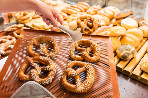 Dama de ventas en panadería vendiendo pretzels y pan
 - Foto, Imagen