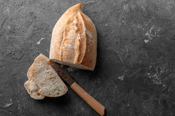 Knife and cut fresh tasty bread on table - 写真・画像