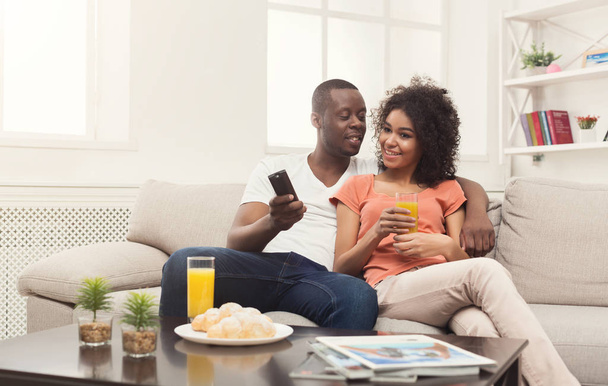 家でテレビを見て幸せなアフリカ系アメリカ人カップル - 写真・画像