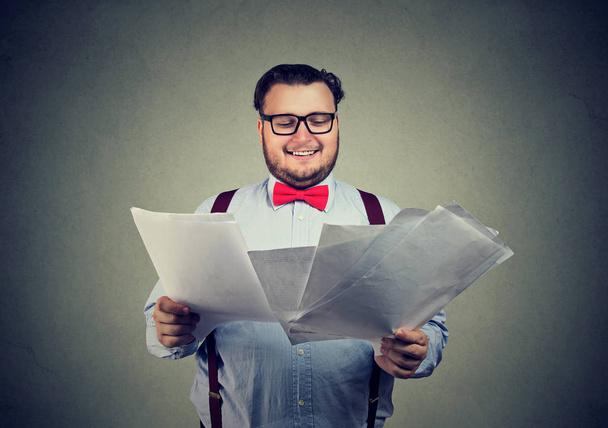 Happy business man in glasses holding pile of documents and looking excited with results of application - 写真・画像