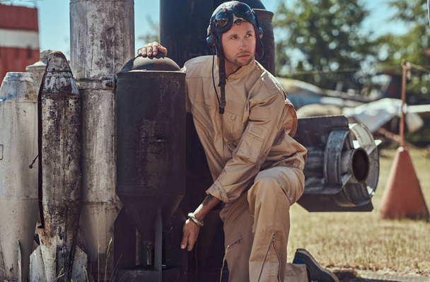 Portrait of a pilot in uniform and flying helmet near to combat bombs for a bomber aircraft in an open-air museum. - Foto, immagini