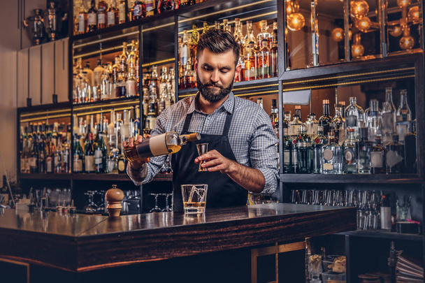 Bir gömlek ve önlük şık acımasız barmen, bir kokteyl bar counter arka plan yapar. - Fotoğraf, Görsel