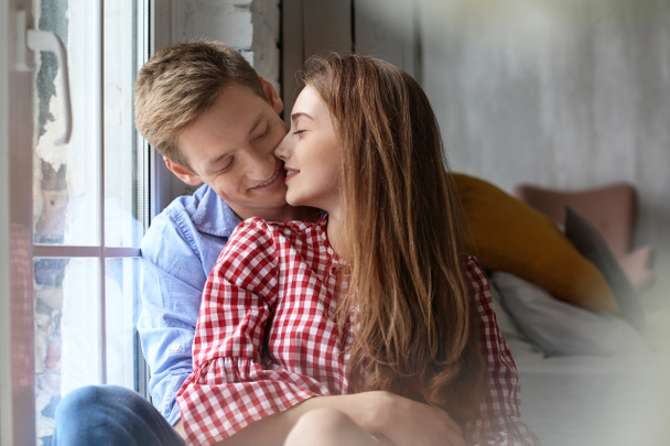 Happy young couple resting near window at home - Foto, Imagen