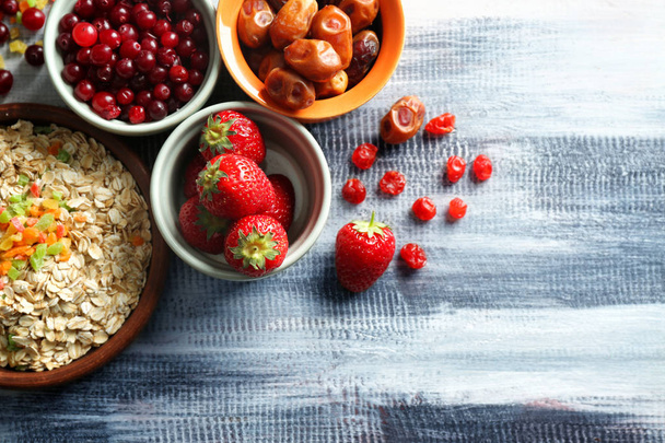 Склад з вівсяними пластівцями, ягодами та сухими фруктами на дерев'яному столі
 - Фото, зображення
