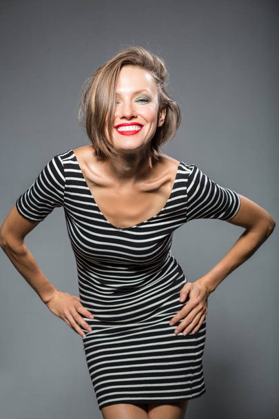 Funny happy woman wearing stripes dress over grey background - 写真・画像
