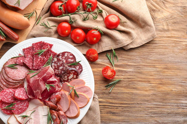 Plate with assortment of delicious deli meats on table - Photo, Image