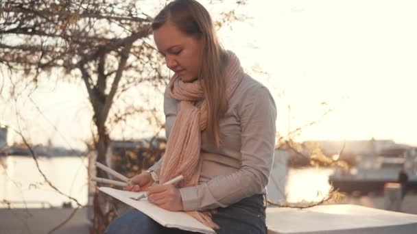 Művész nő a rajz kép ül a parkban a naplemente - Felvétel, videó