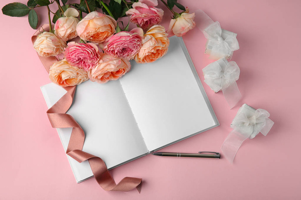 Composition with beautiful flowers and notebook on color background - Photo, Image