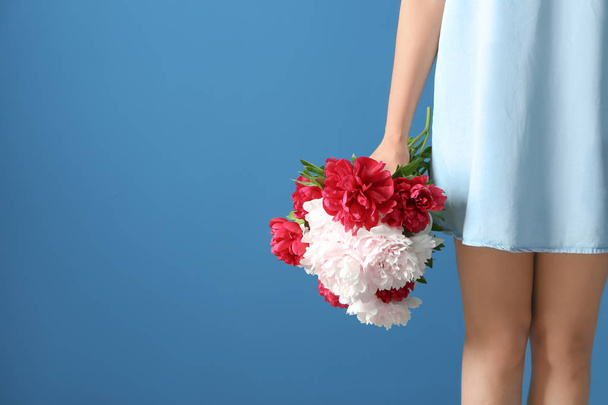 Young woman holding beautiful peonies on color background - Фото, изображение