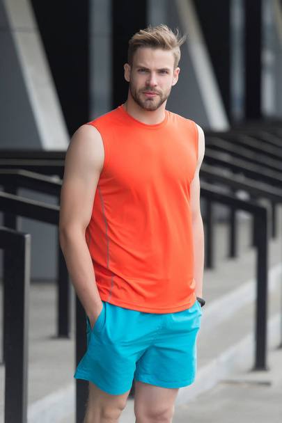 Man with bristle on serious face in sporty wear, urban background. Sport fashion concept. Guy bearded and attractive cares about appearance. Man with beard or unshaven guy in stylish sport clothes - 写真・画像