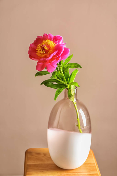Vase with beautiful peony flower on table against color background - Photo, image