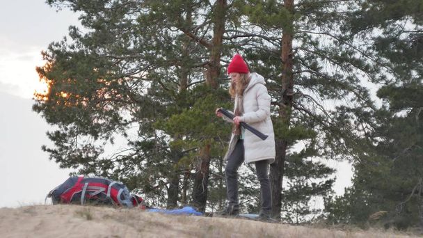 Attraente giovane donna turistica in un cappello rosso raccoglie una tenda turistica vicino alla foresta sulla costa 4k
 - Foto, immagini
