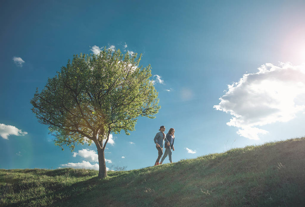 Beloved couple walking together on green hill - Фото, изображение