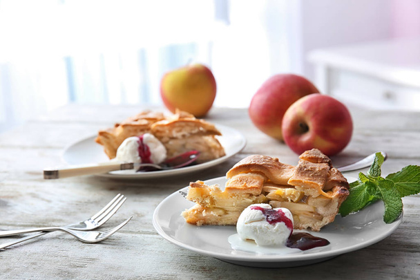 Placa con trozo de delicioso pastel de manzana y helado en la mesa de madera
 - Foto, Imagen