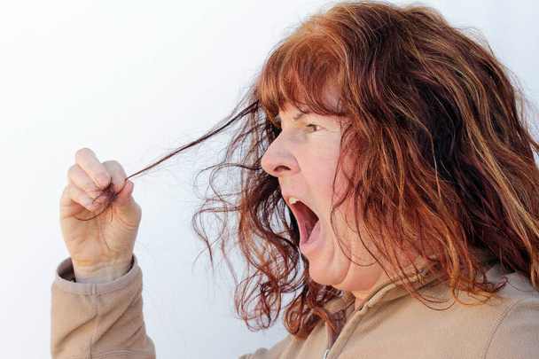 Een bejaarde vrouw ontdekt dat haaruitval. Een vrouw is geschokt op haar haaruitval - Foto, afbeelding