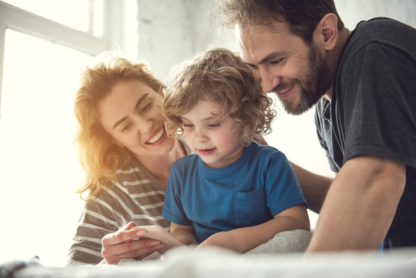 Smiling parents and kid are looking at phone screen - Foto, Imagem