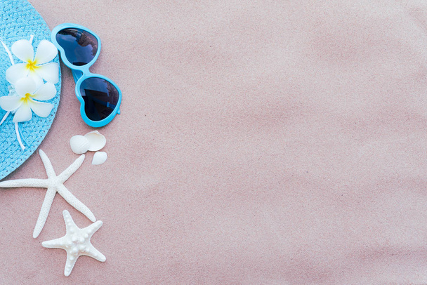 Accessoires de plage, y compris lunettes de soleil bleues, étoile de mer, fleur et chapeau bleu plage sur fond de plage de sable pour vacances d'été et concept de vacances
. - Photo, image