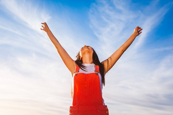 Счастливая и свободная молодая женщина поднимает руки на голубом фоне неба. Свободу. Здоровый образ жизни. Молодежь
 - Фото, изображение