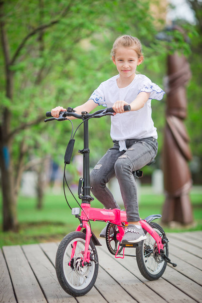 Adorable girl riding a bike at beautiful summer day outdoors - Photo, Image