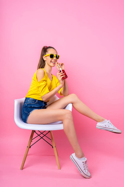 Teenage girl sitting in chair and drinking beverage - Valokuva, kuva