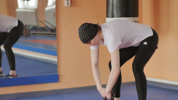 Woman kickboxer is training in a sports studio with dumbbells - Zdjęcie, obraz