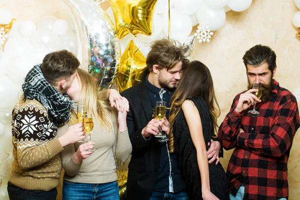 Muži a ženy pít šampaňské, strana. Přátel oslavit Vánoce nebo nový rok. Dva milenci líbat. Ženy a muži mají strany oslava. Vánoční a novoroční svátky - Fotografie, Obrázek