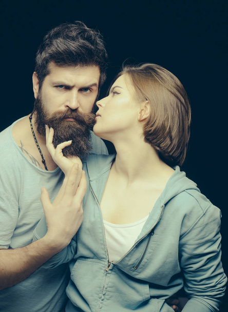 Fashion shot of couple after haircut. Barbershop concept. Woman on mysterious face with bearded man, black background. Man with stylish beard and mustache and girl with fresh haircut, new hairstyle - Foto, Imagem