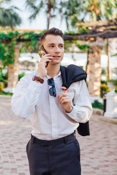 Young businessman talking on his phone outdoors in a tropical country - Valokuva, kuva