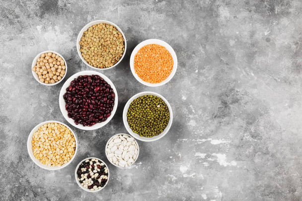 Assortment of beans (red lentil, green lentil, chickpea, peas, red beans, white beans, mix beans, mung bean) on gray background. Top view, copy space. Food background - Foto, Bild